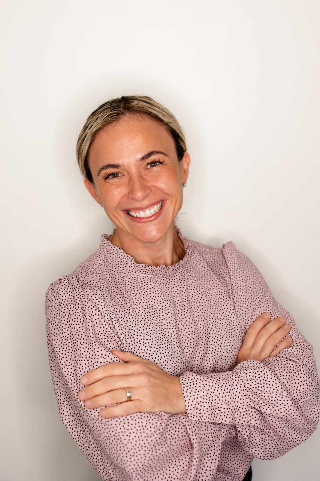 Woman with floral print shirt smiling with her arms crossed