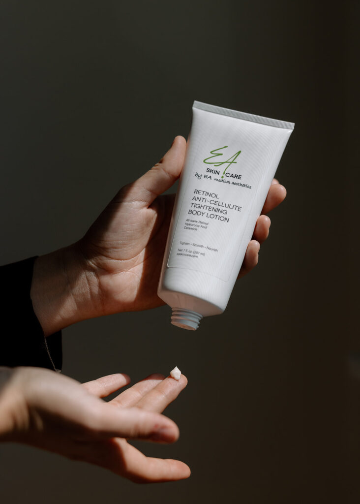 A person shows EA Skincare Retinol Anti-Cellulite Tightening Body Lotion on a fingertip