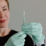 Kasia prepares for an injection with gloved hands and a syringe.