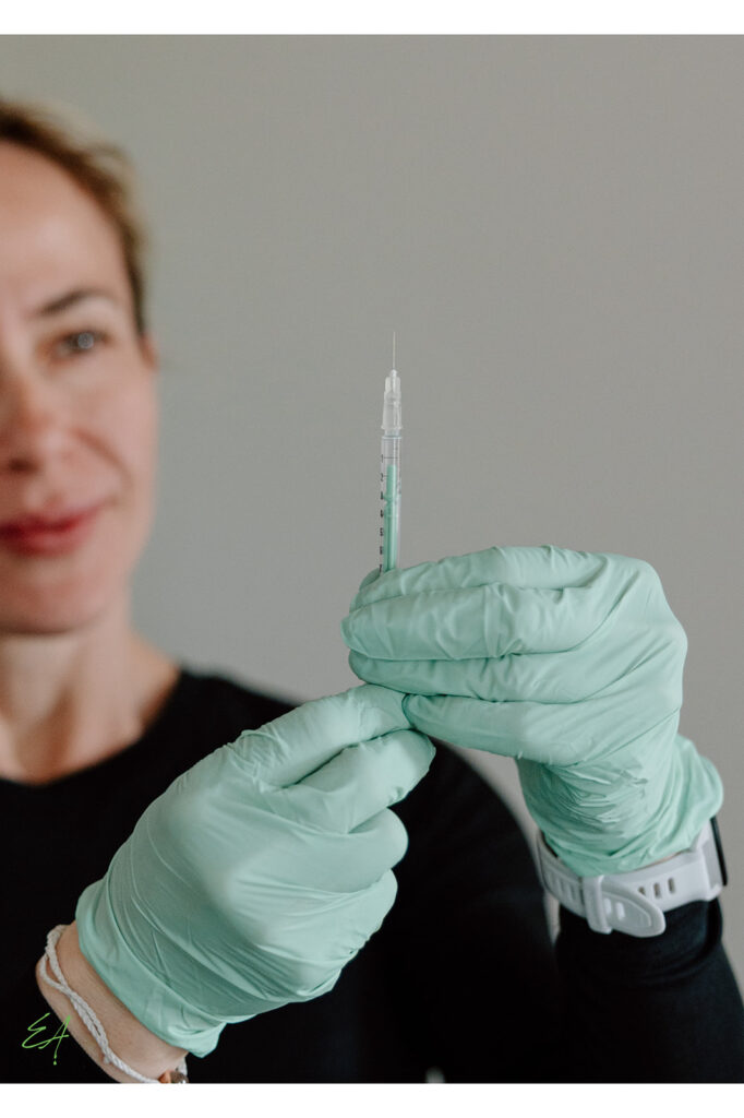 Kasia prepares for an injection with gloved hands and a syringe.